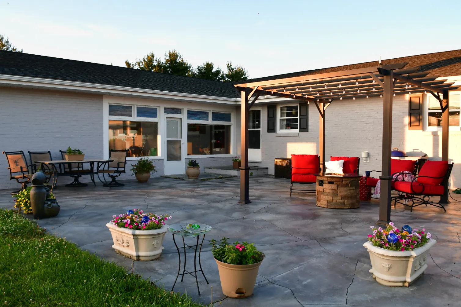 A patio area with outdoor furniture, a pergola, and various potted plants.