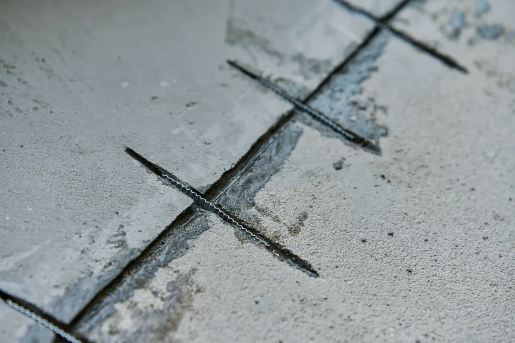 Close-up of a concrete surface with cuts and fissures, showing uneven texture and depth.